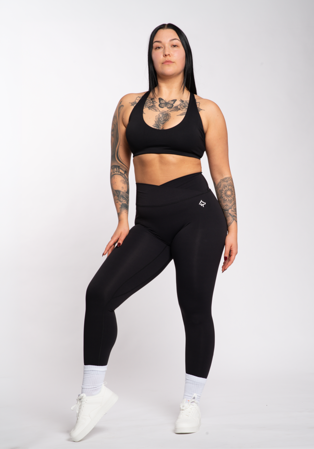 Woman in black high-performance gym leggings and sports bra, styled for training and active lifestyle