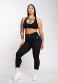 Woman in black high-performance gym leggings and sports bra, styled for training and active lifestyle