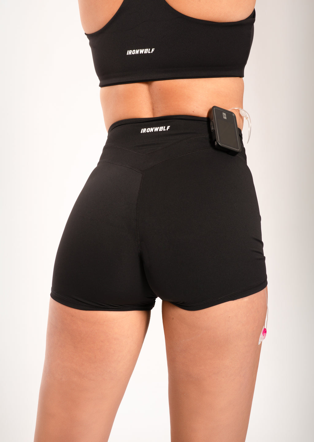 Woman wearing black IRONWØLF gym shorts and sports bra with phone pocket, ideal for training and fitness