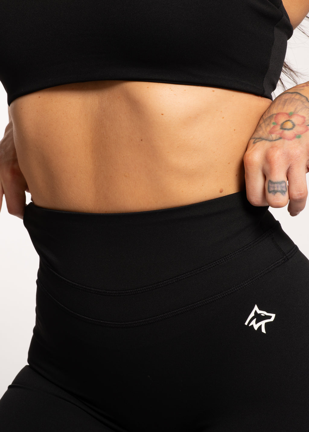 Black high-waisted gym leggings with wolf logo, paired with crop top, ideal for training and active lifestyle.