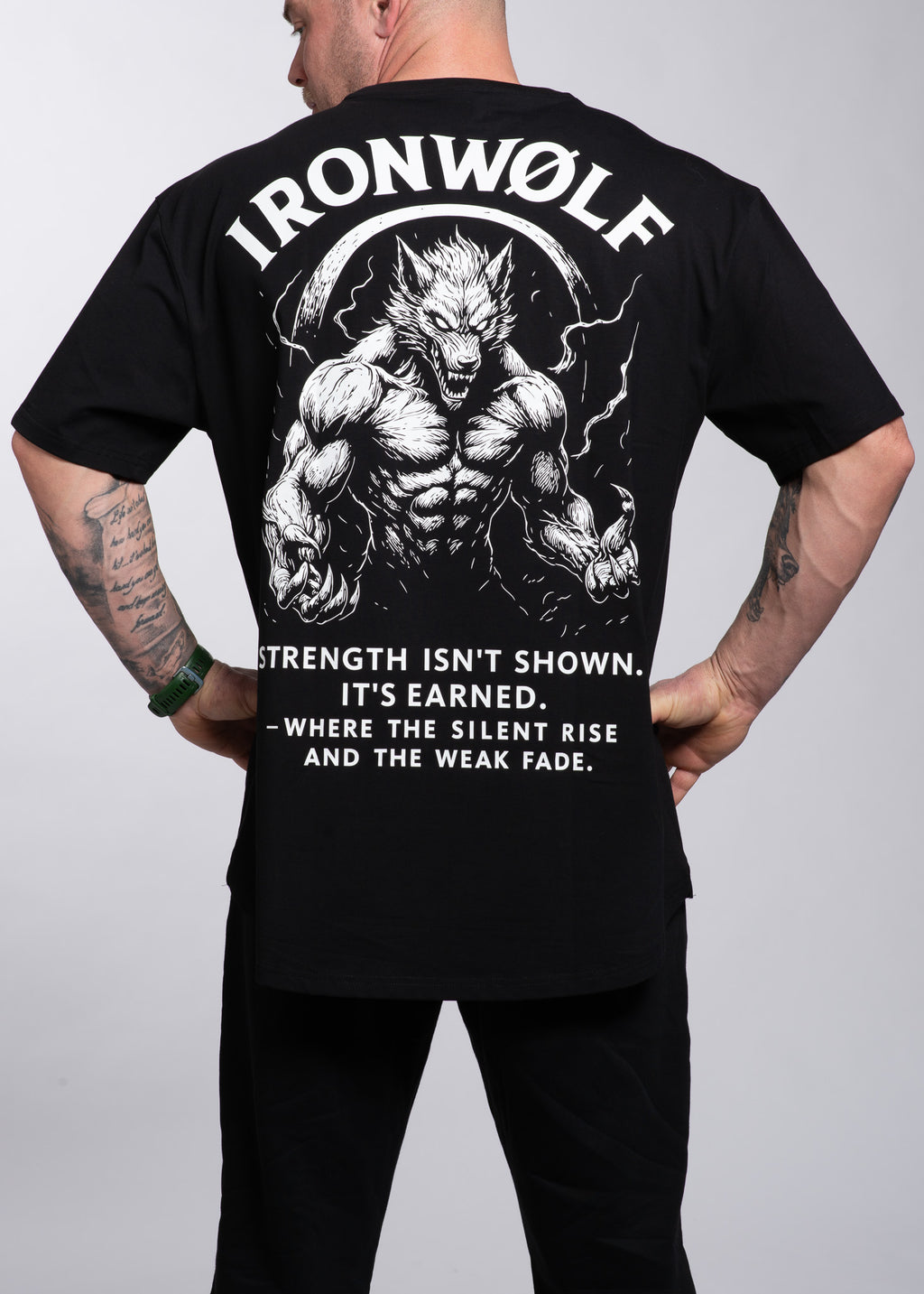 Man wearing black gym t-shirt with muscular wolf graphic and motivational quote for strength training