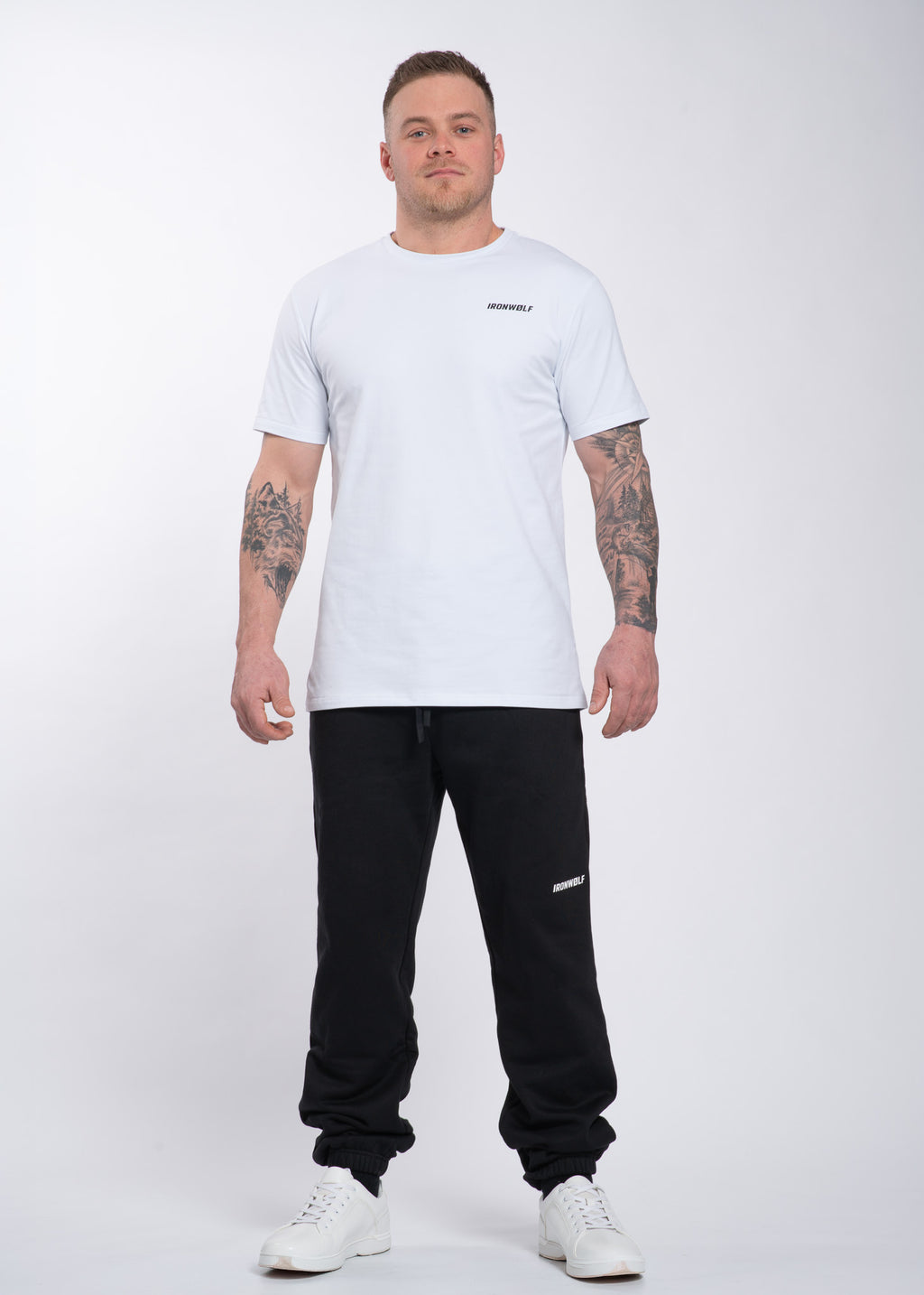 Man wearing white IRONWØLF gym t-shirt and black sweatpants, ideal for training and lifestyle comfort.