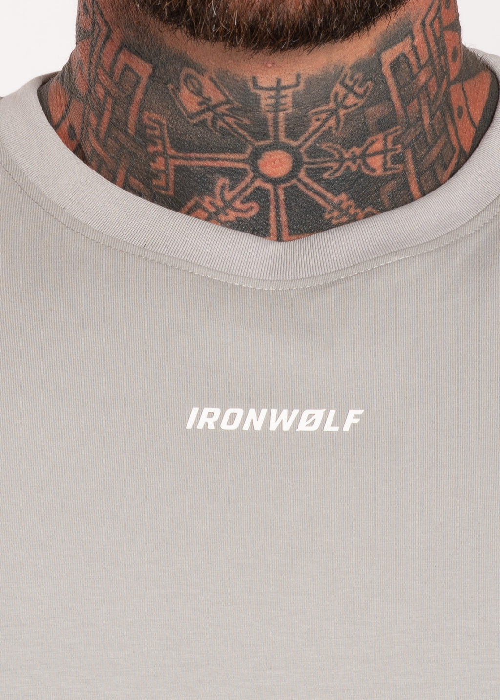 Man wearing IRONWØLF gym shirt with neck tattoo, showcasing activewear for training and lifestyle.
