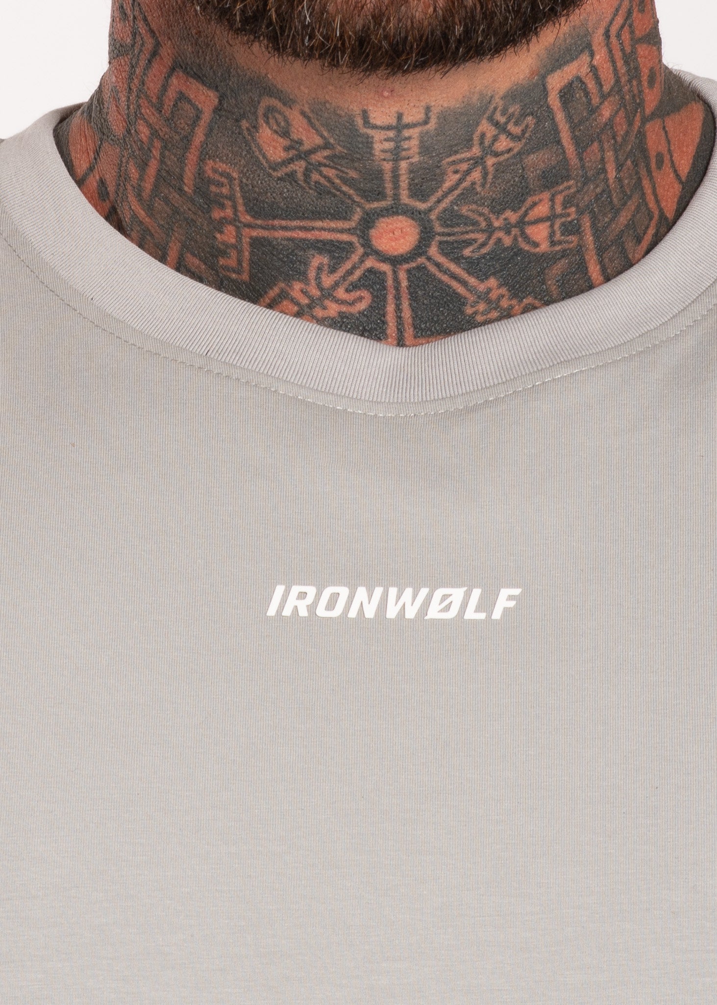 Man wearing IRONWØLF gym shirt with neck tattoo, showcasing activewear for training and lifestyle.