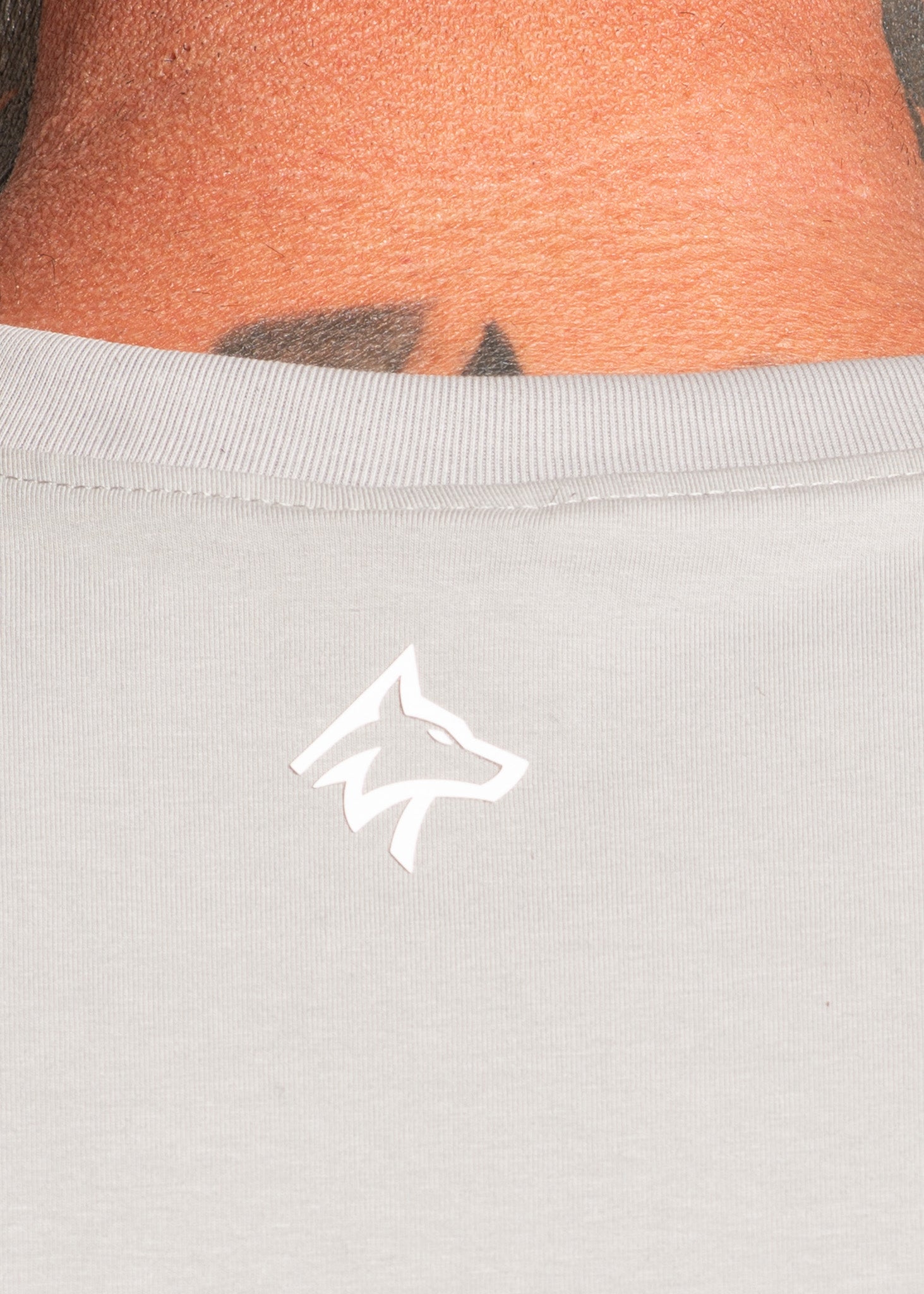 Light gray gym wear with white wolf logo, worn by person with tattooed skin