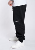 Black IRONWØLF joggers with white logo, paired with white sneakers and a white tee for gym or streetwear style.