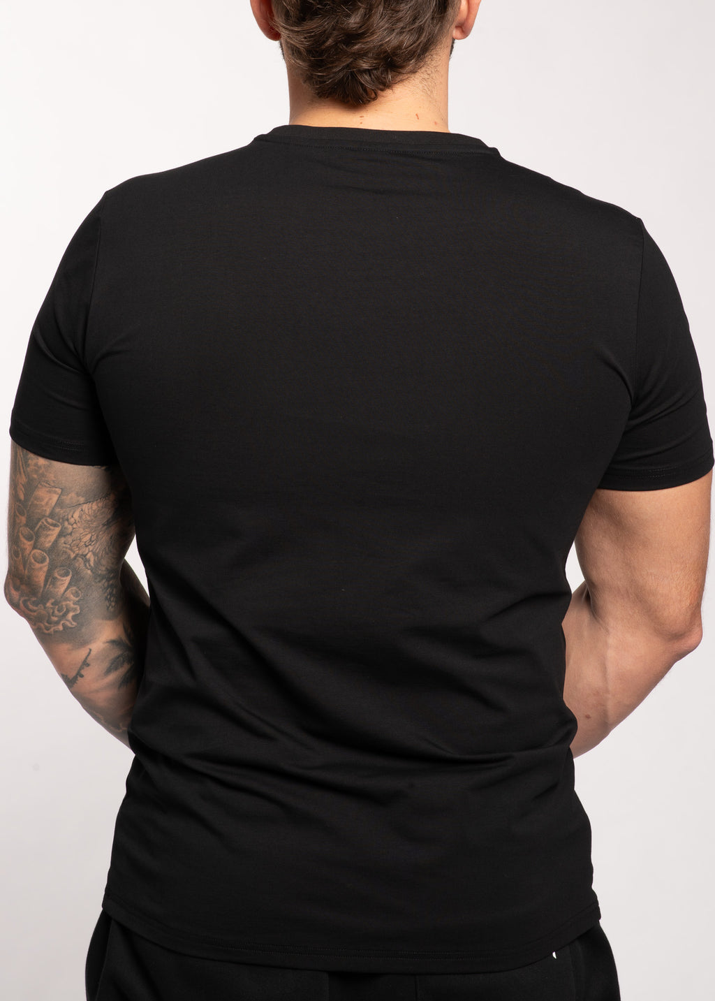 Men's black gym t-shirt back view, muscle fit, tattooed arm, activewear for training and lifestyle