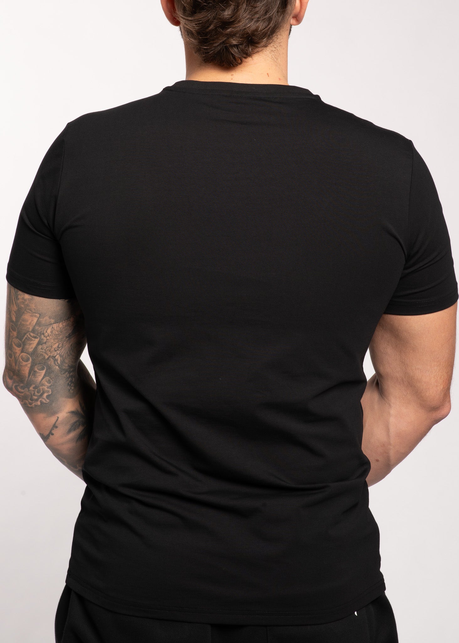Men's black gym t-shirt back view, muscle fit, tattooed arm, activewear for training and lifestyle