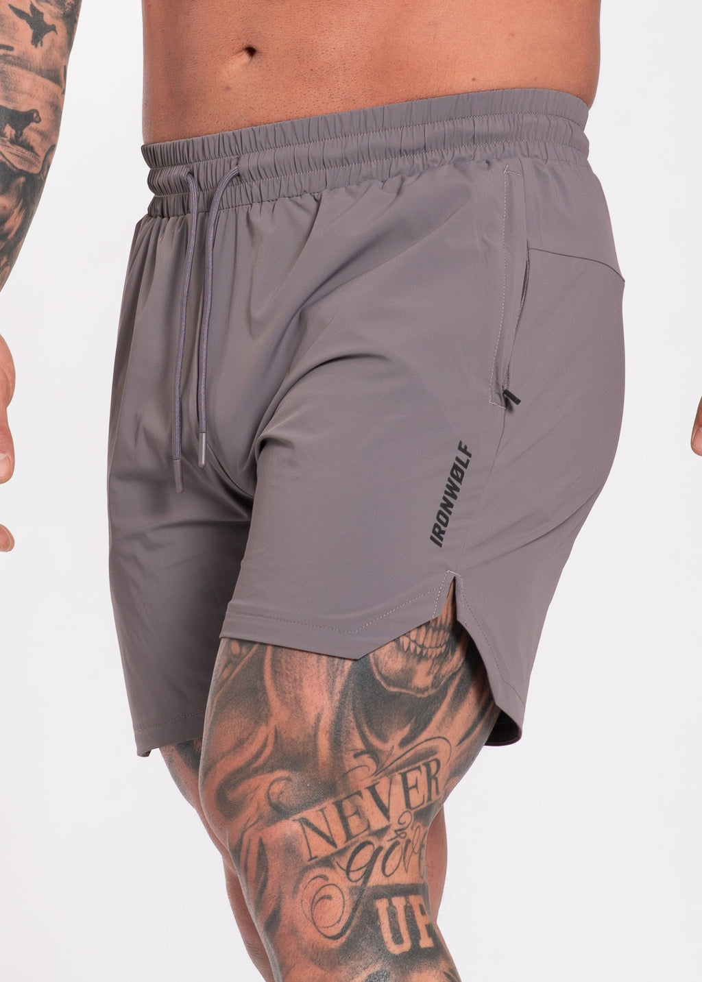 Gray gym shorts with drawstring waist, side pocket, and IRONWØLF logo, worn by tattooed athlete