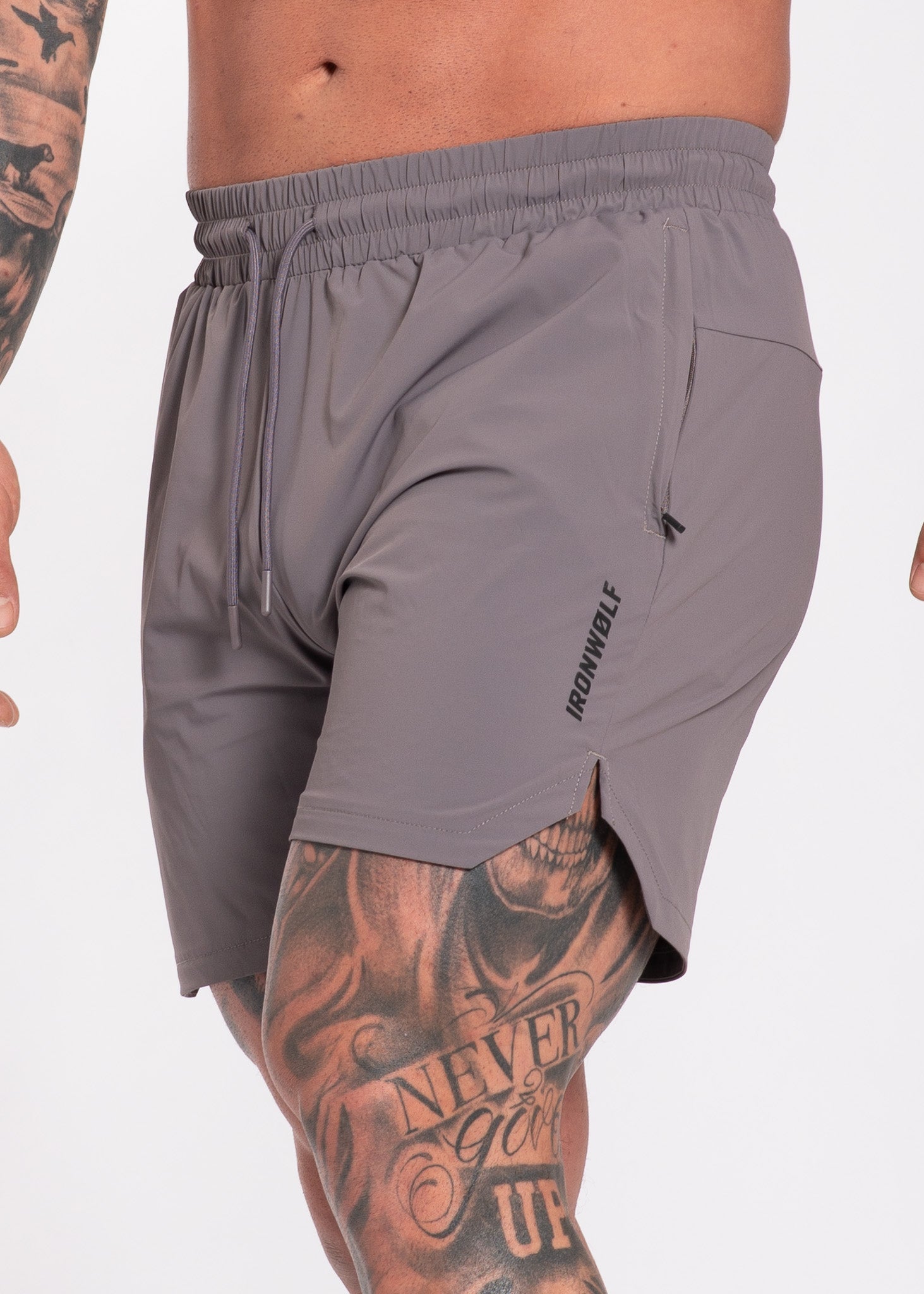 Gray gym shorts with drawstring waist, side pocket, and IRONWØLF logo, worn by tattooed athlete