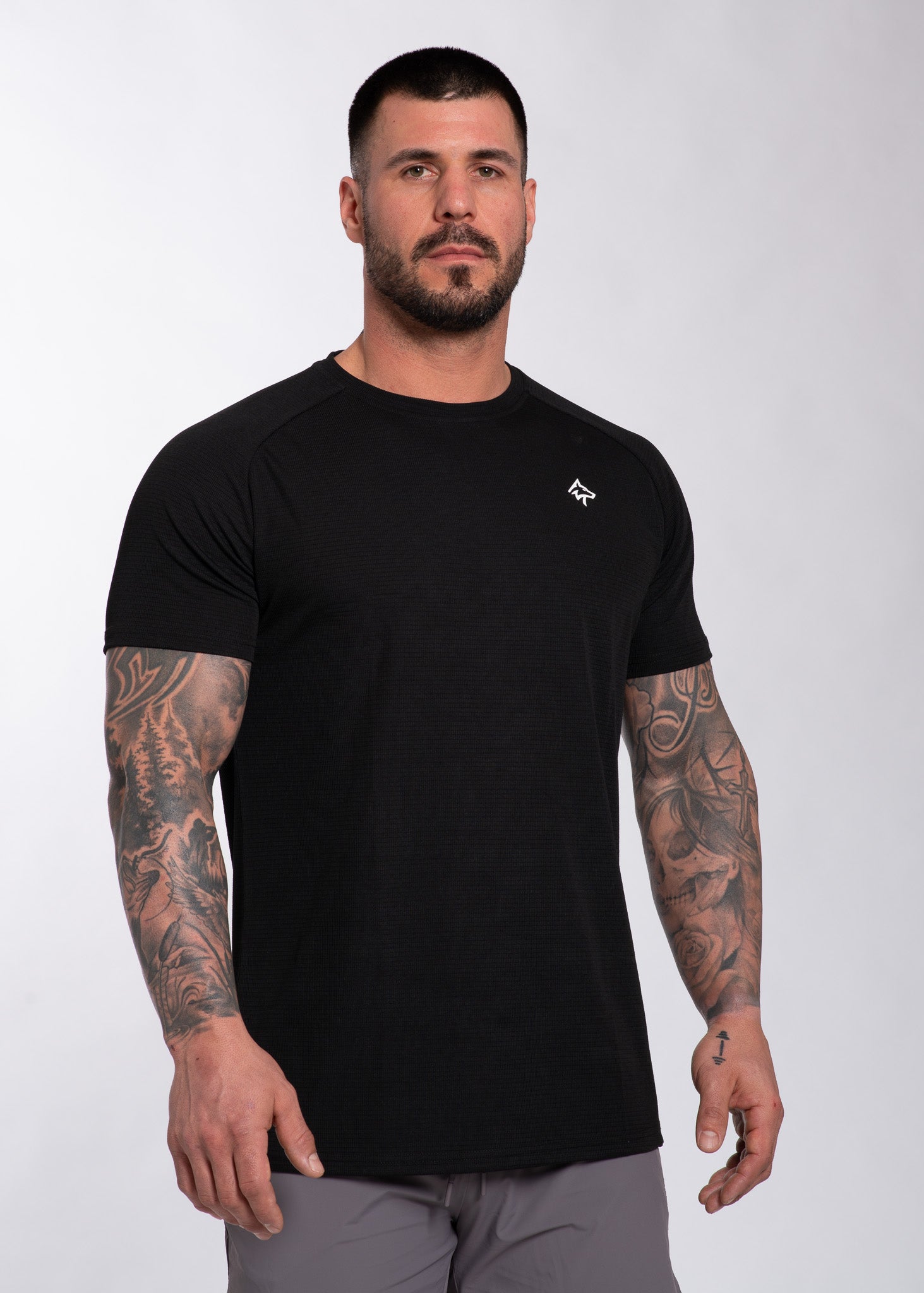 Muscular man in black performance gym shirt with textured fabric and small logo, ideal for training and active lifestyle