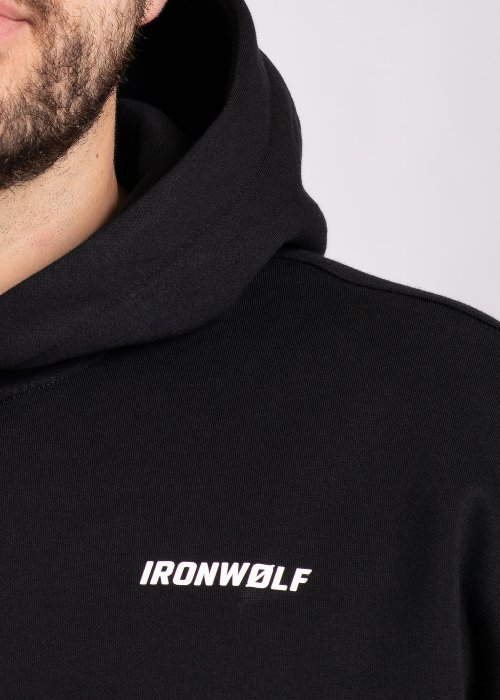Man wearing black IRONWØLF hoodie with chest logo, gym wear for training and lifestyle