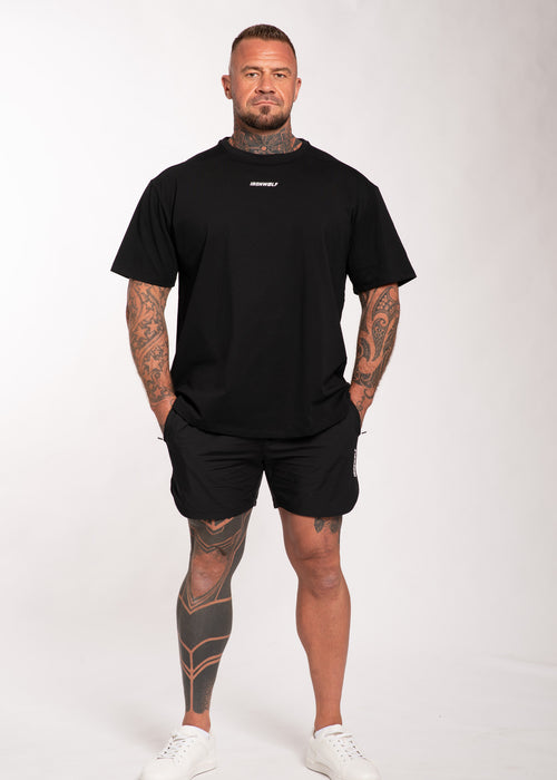 Man in black IRONWØLF gym t-shirt and shorts, showcasing athletic wear for training and lifestyle