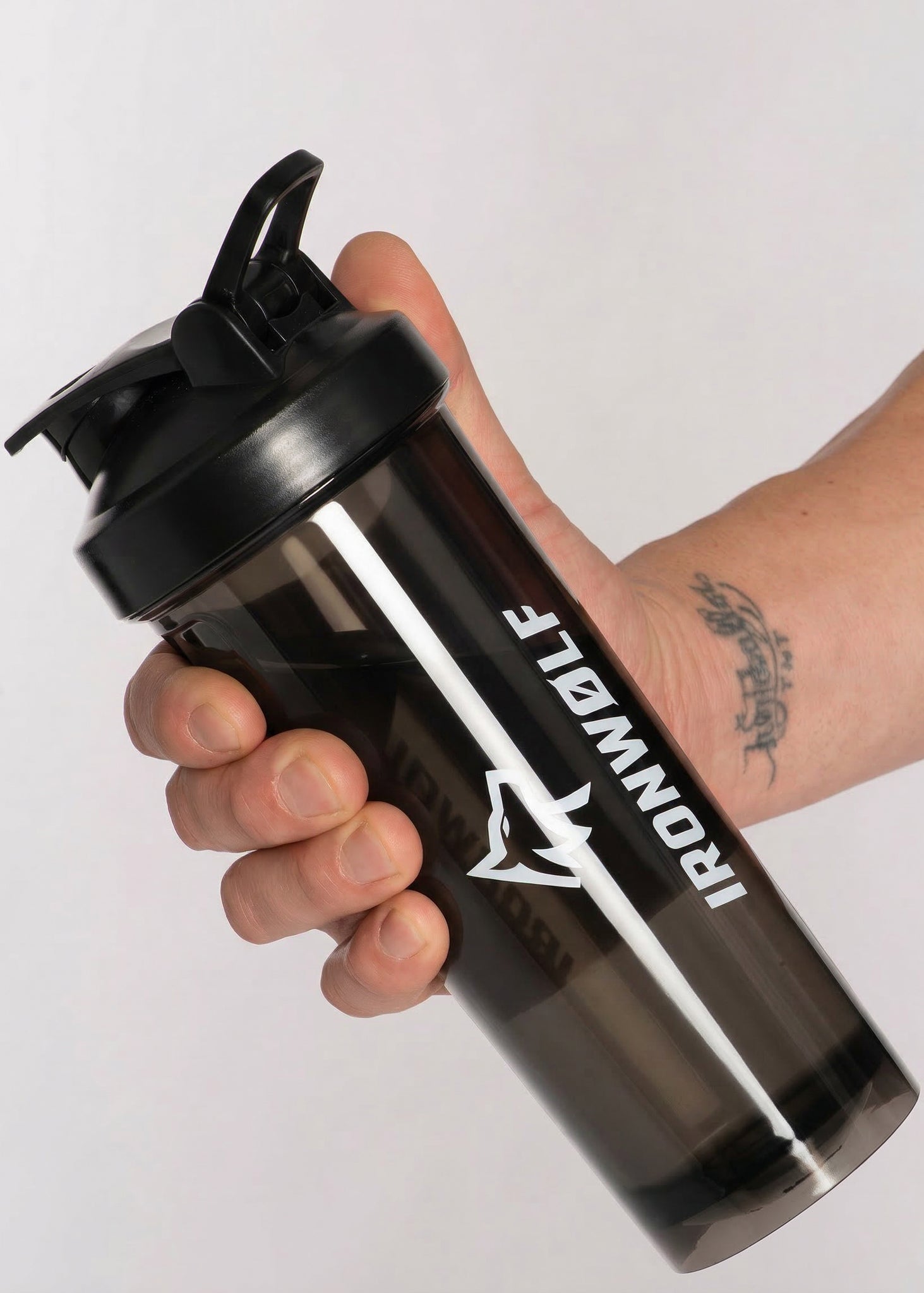 Black IRONWØLF shaker bottle with white logo, held in hand for gym or workout use