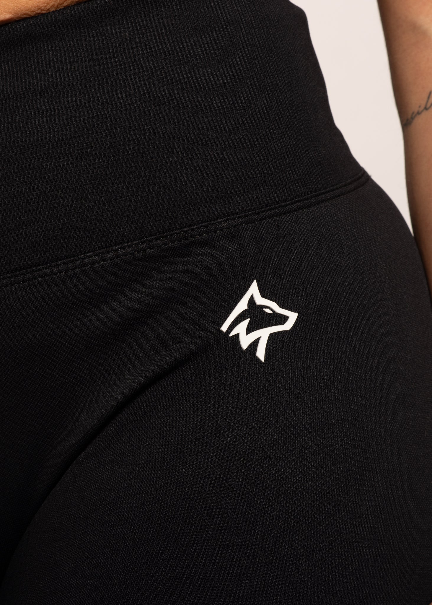 Black high-waisted gym leggings with white wolf logo, designed for comfort and performance during workouts.