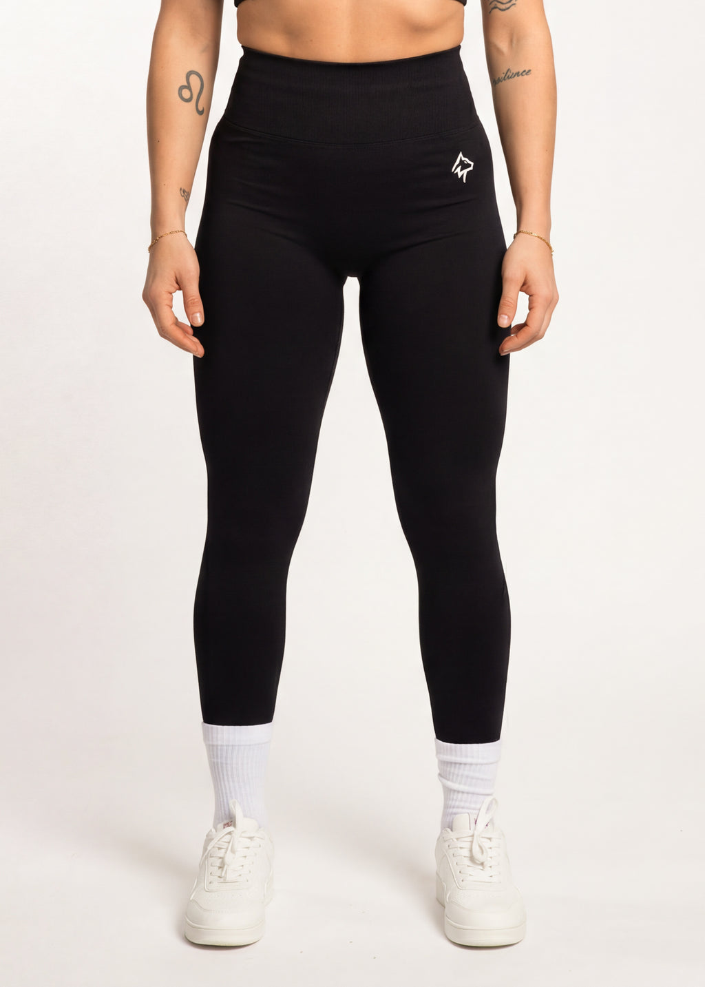 Black high-waisted gym leggings with white logo, paired with white sneakers and socks for workout or casual wear