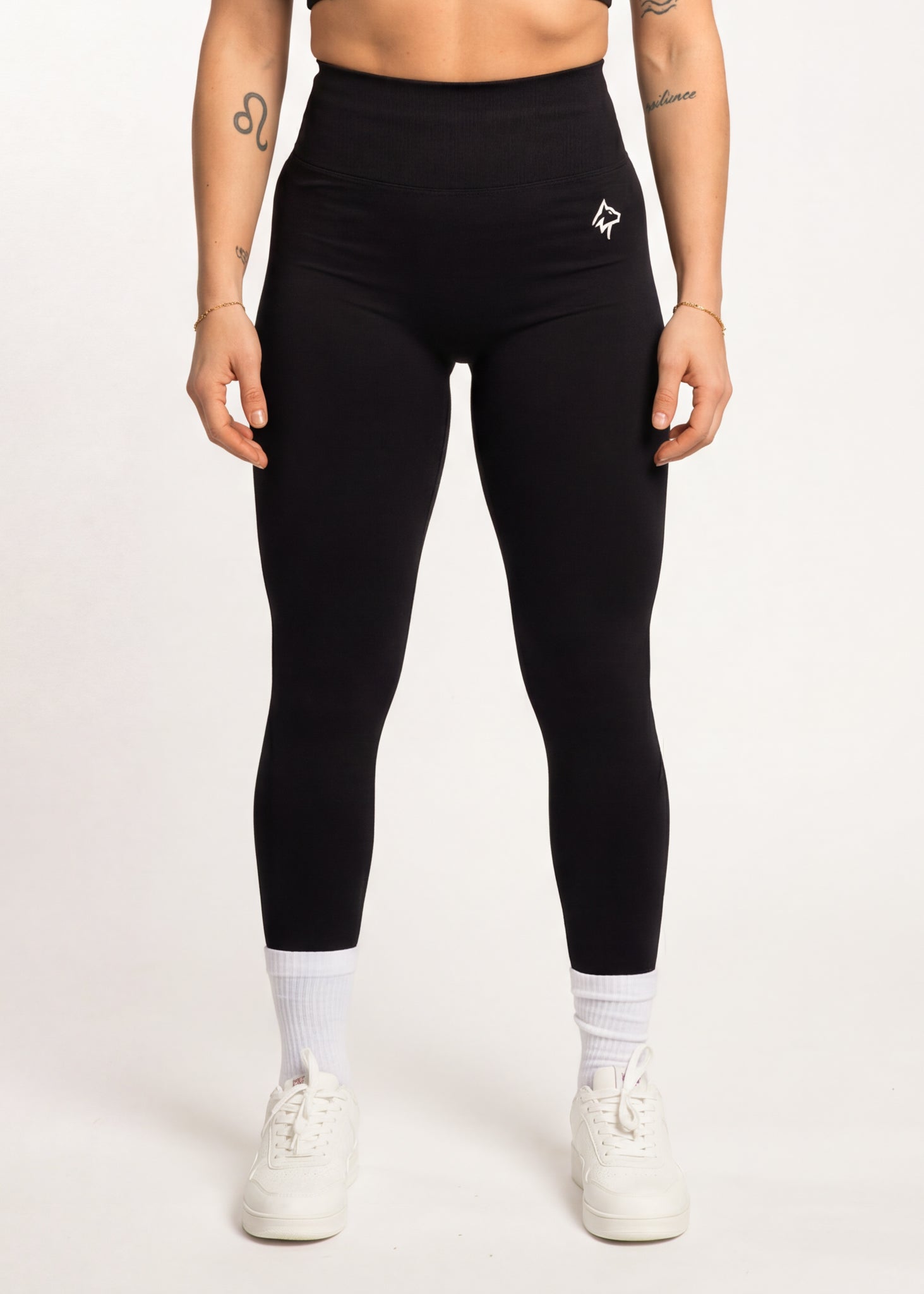 Black high-waisted gym leggings with white logo, paired with white sneakers and socks for workout or casual wear