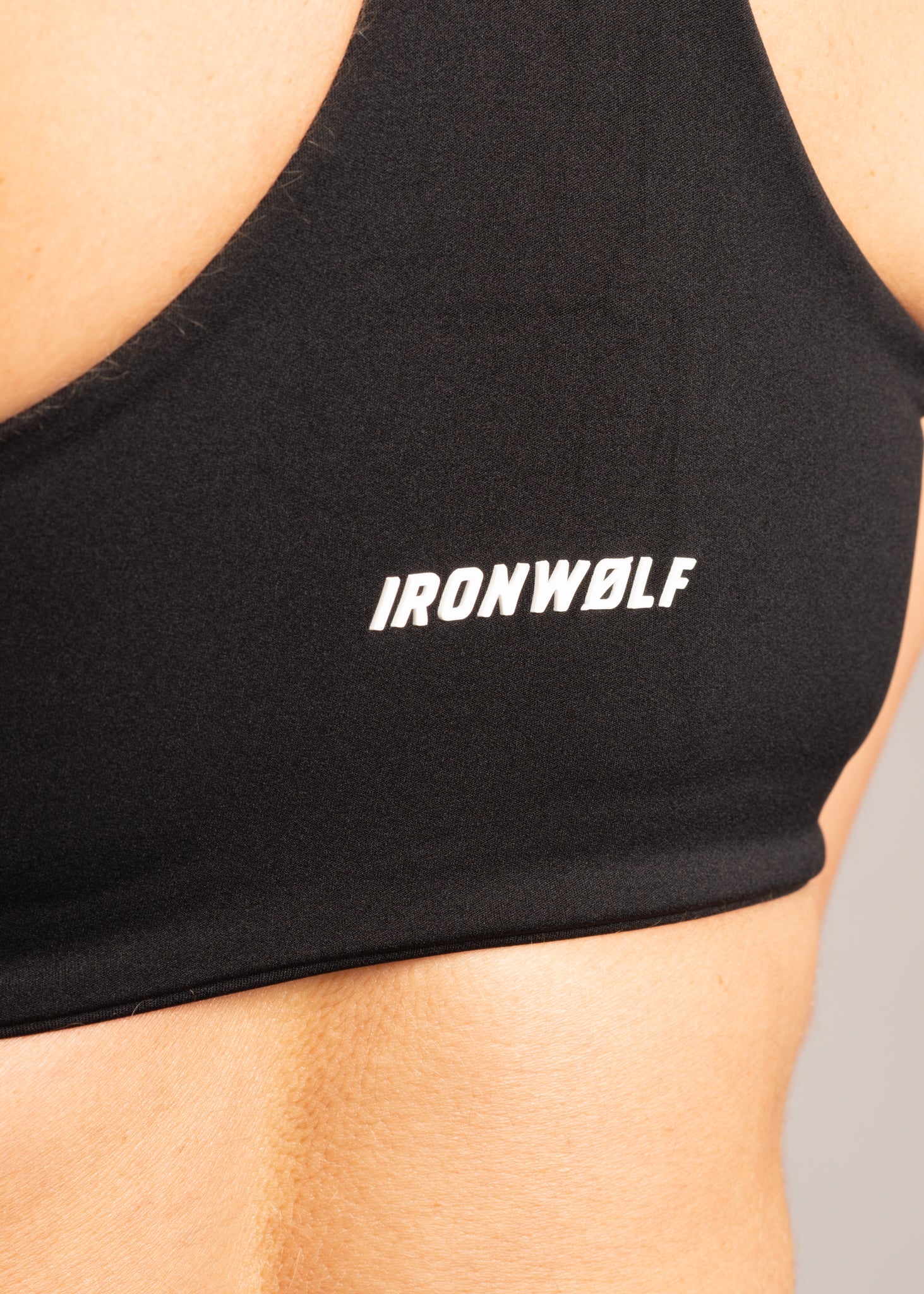 Black IRONWØLF sports bra with white logo, designed for gym training and active lifestyle comfort.