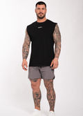 Man in black sleeveless gym shirt and gray shorts, showcasing tattooed arms and legs for workout wear.