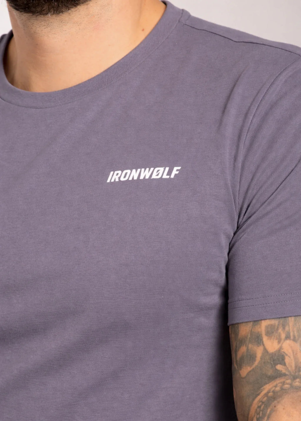 Man wearing gray IRONWØLF gym t-shirt with chest logo, ideal for training and active lifestyle