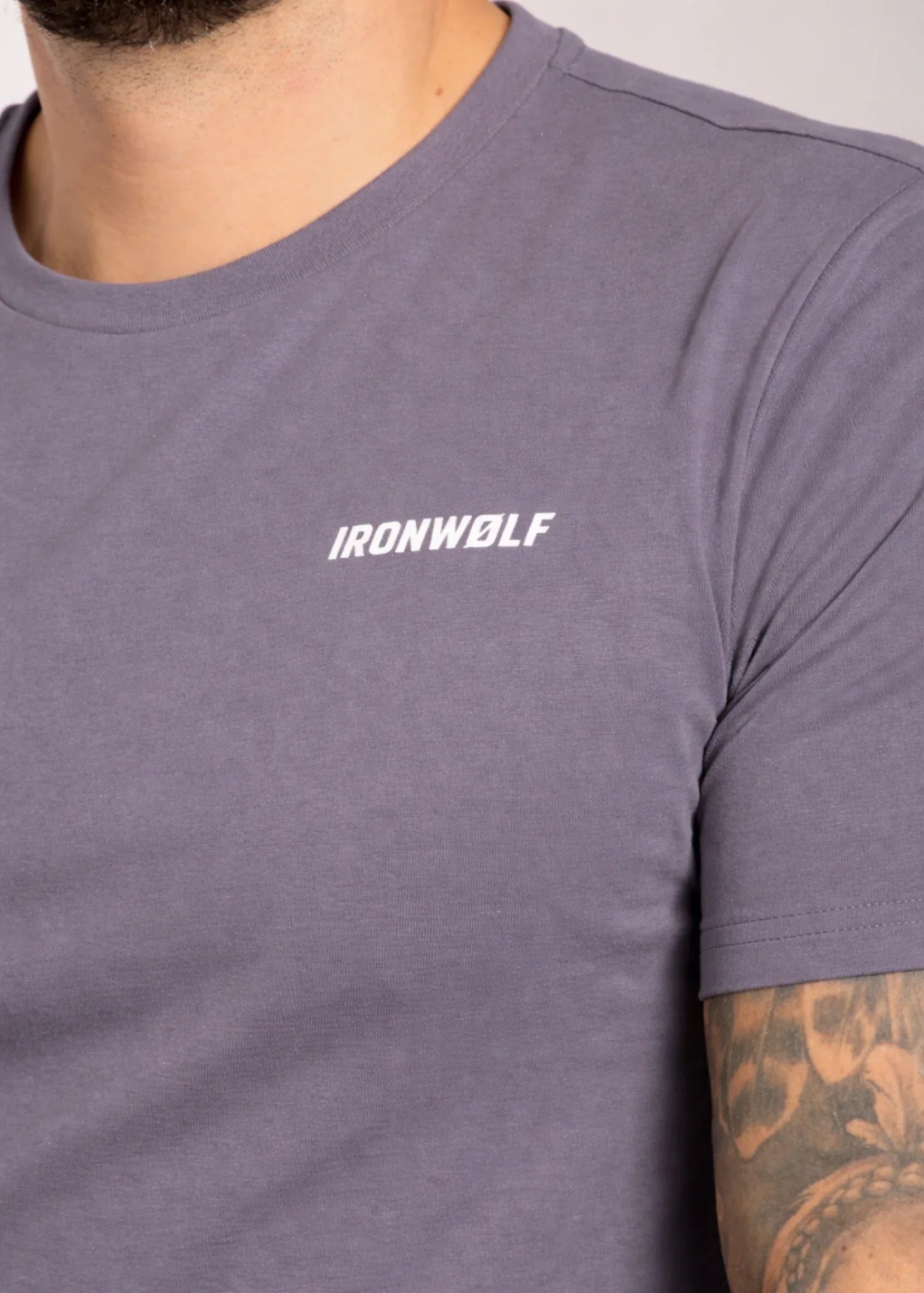 Man wearing gray IRONWØLF gym t-shirt with chest logo, ideal for training and active lifestyle