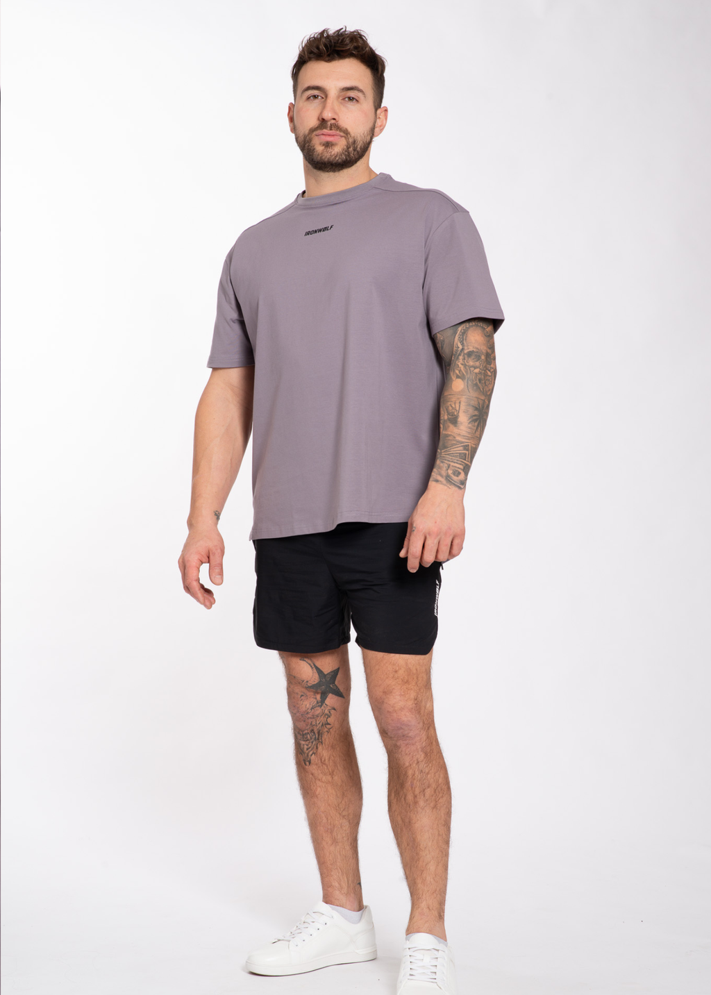 Man wearing gray IRONWØLF gym t-shirt, black shorts, white sneakers — fitness activewear for training & lifestyle