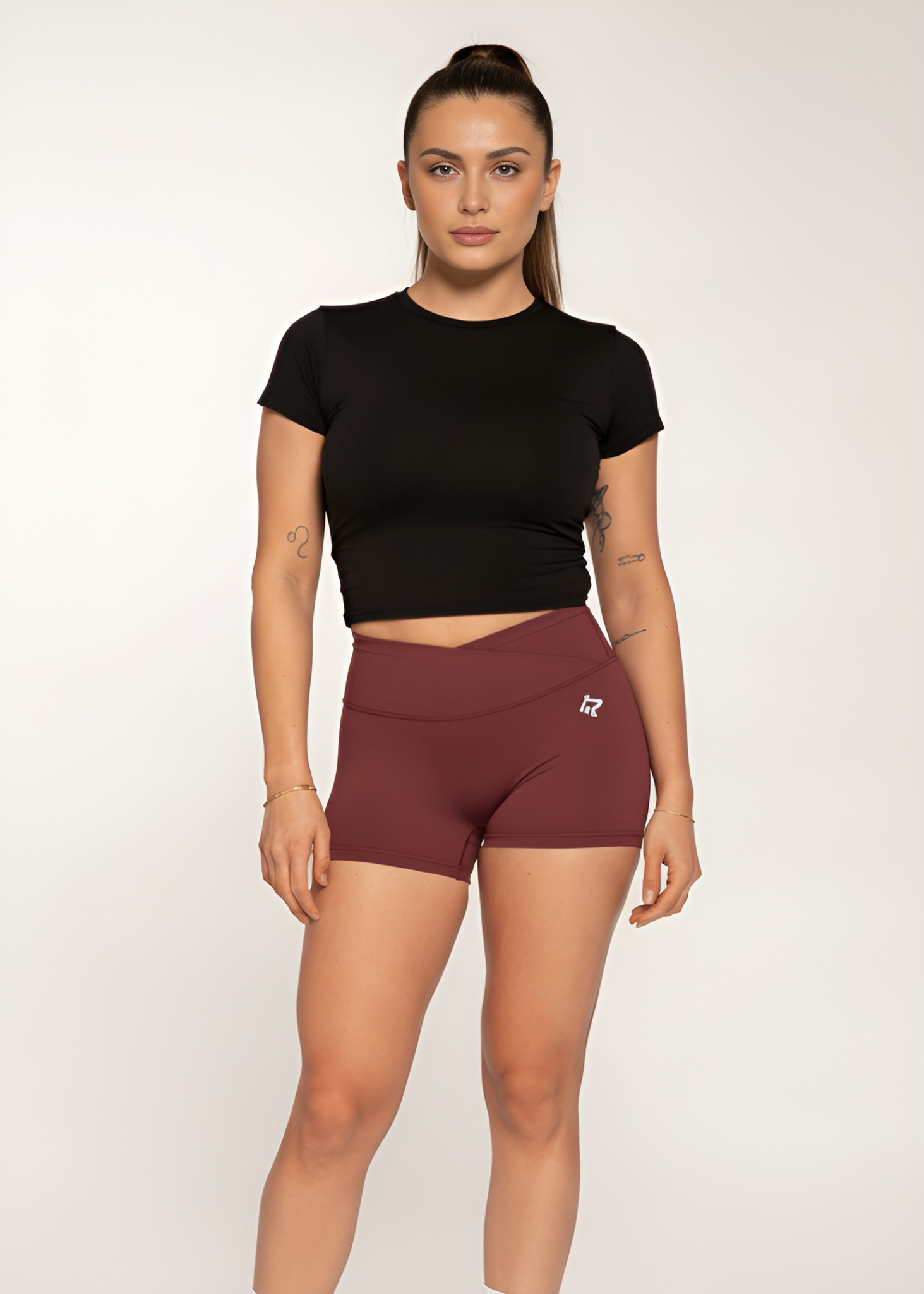 Woman in black crop top and burgundy high-waisted gym shorts for training and fitness