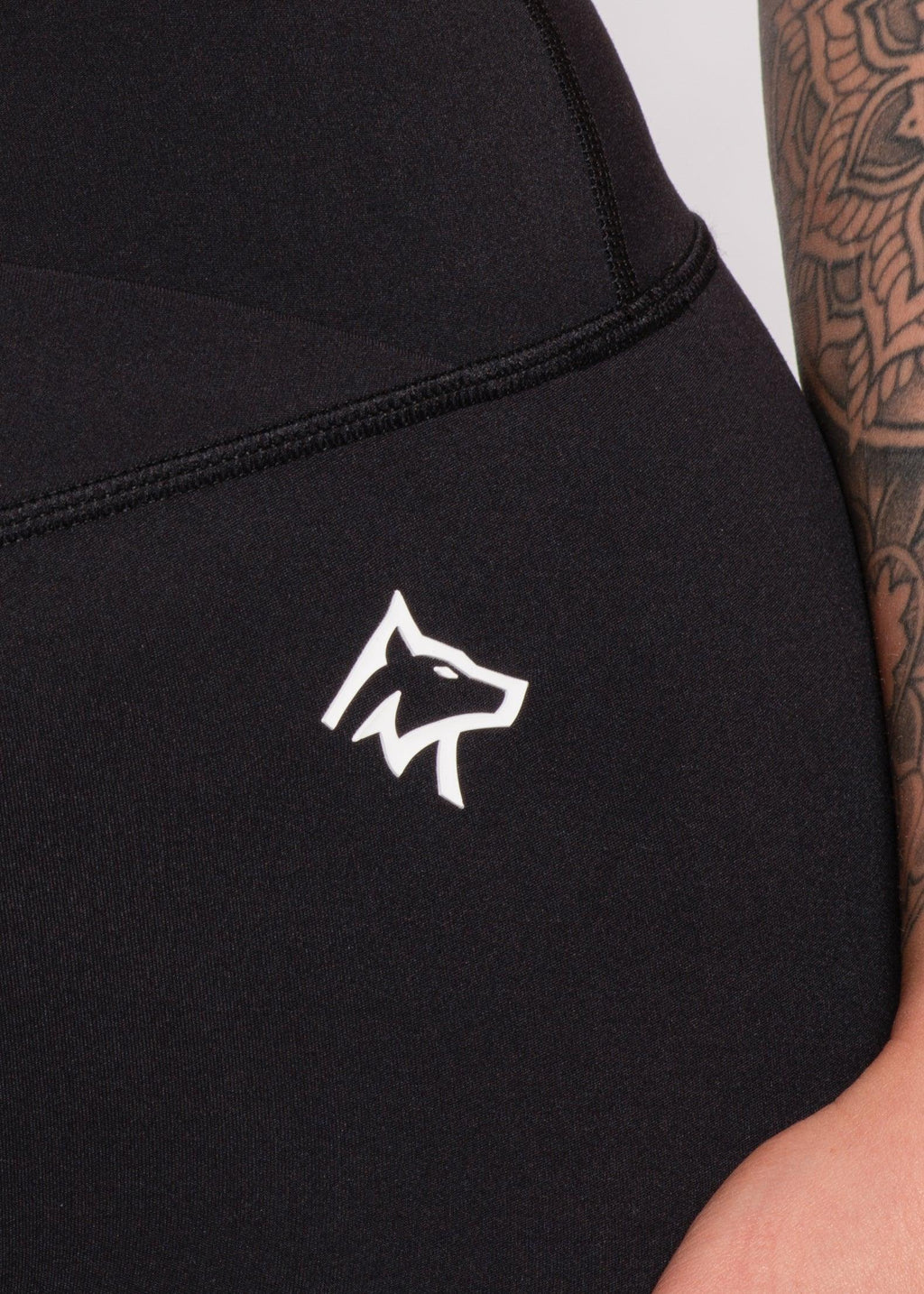 Black high-waisted gym leggings with white wolf logo, featuring tattooed arm detail for active wear style.