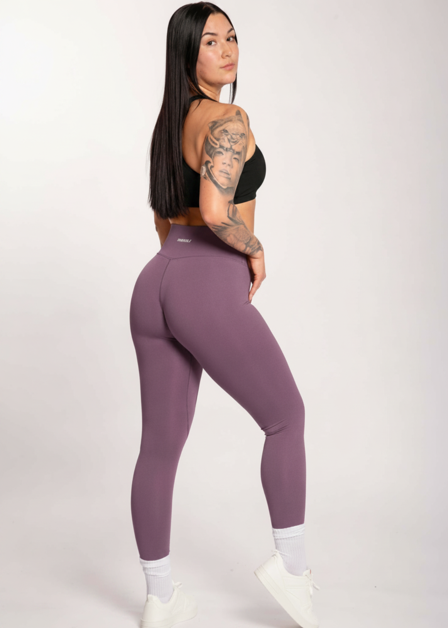 Woman in purple high-waisted gym leggings and black sports bra, showcasing athletic wear for training and lifestyle.