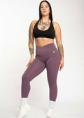 Woman in black sports bra and mauve high-waisted leggings, styled for gym or active lifestyle wear