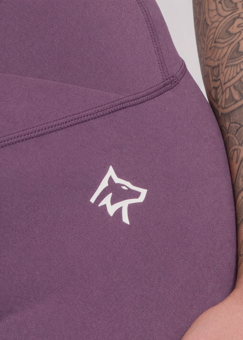 Purple gym hoodie with white wolf logo, worn by person with tattooed arm, ideal for training and active lifestyle.