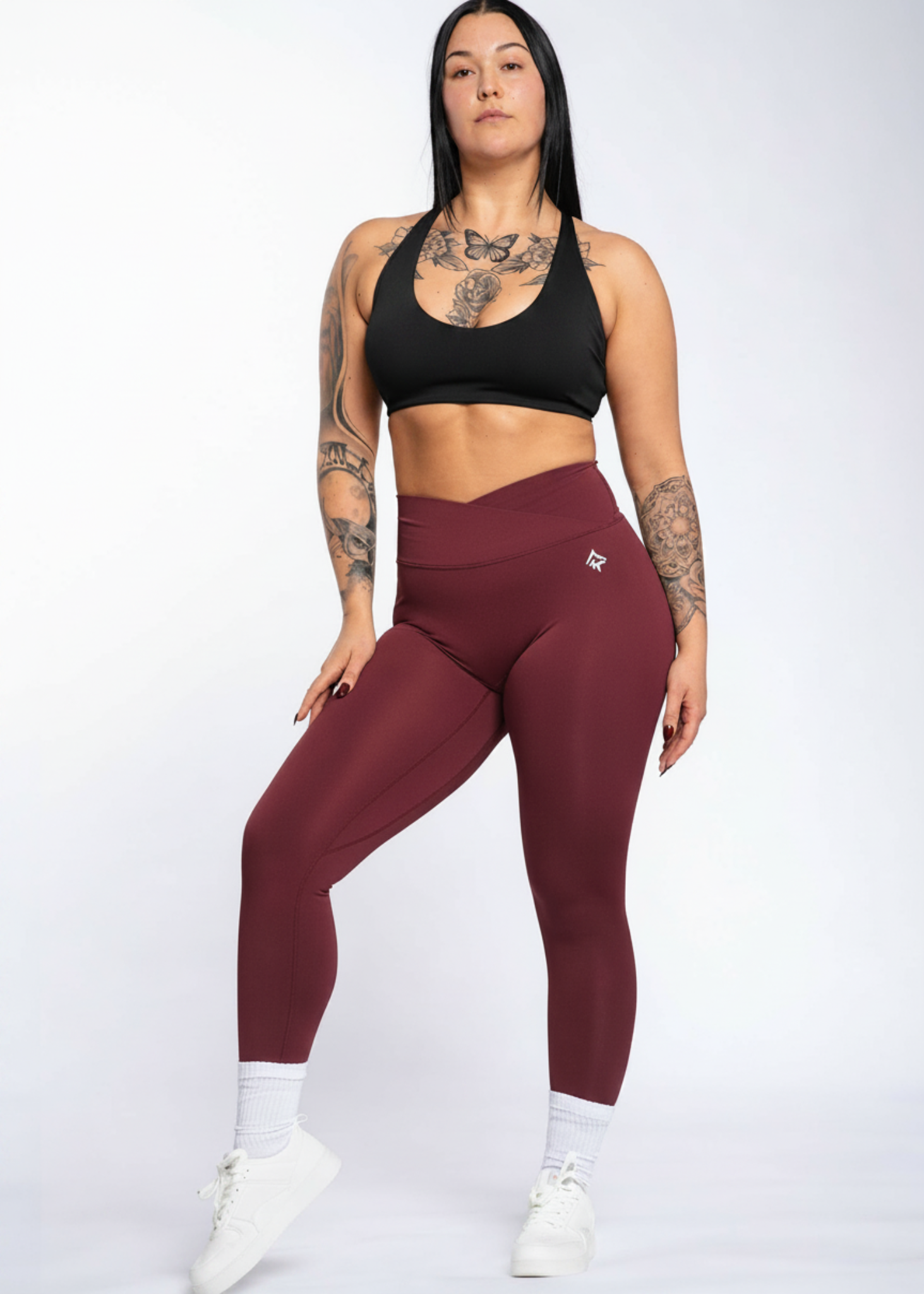 Woman in black sports bra and burgundy high-waisted leggings, showcasing gym wear for training and comfort.