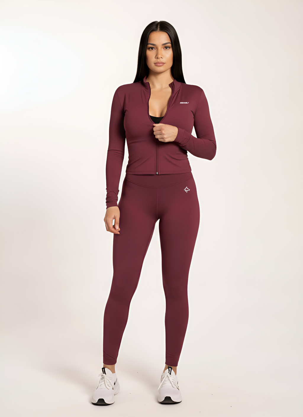 Woman in burgundy gym wear set with zip-up top and leggings, ideal for training and active lifestyle