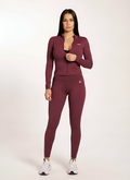 Woman in burgundy gym wear set with zip-up top and leggings, ideal for training and active lifestyle