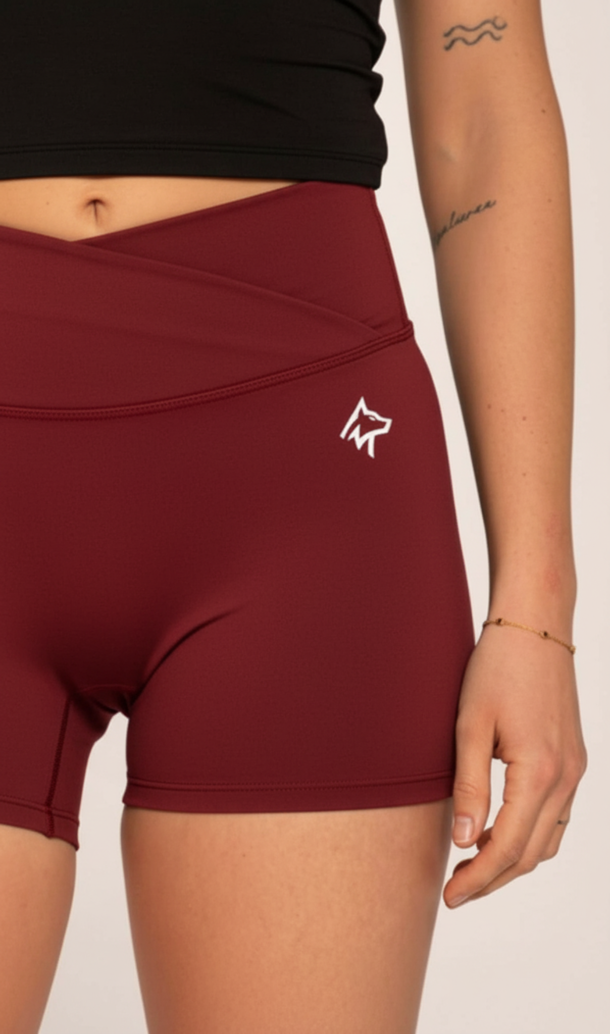 Burgundy high-waisted gym shorts with white wolf logo, paired with black crop top for workout or active lifestyle.