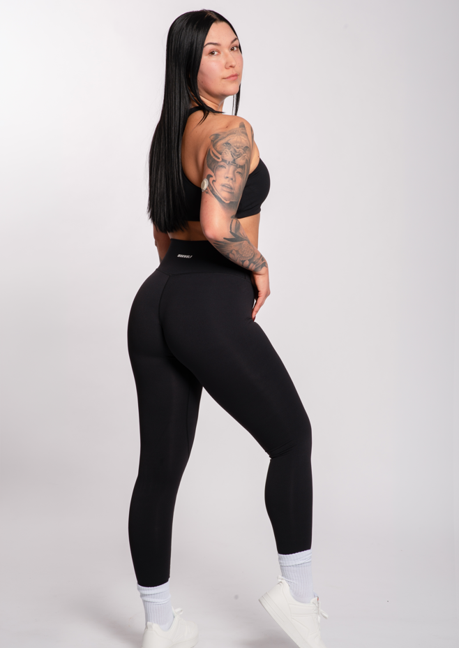 Woman in black high-waisted gym leggings and sports bra, showcasing athletic activewear for training and lifestyle